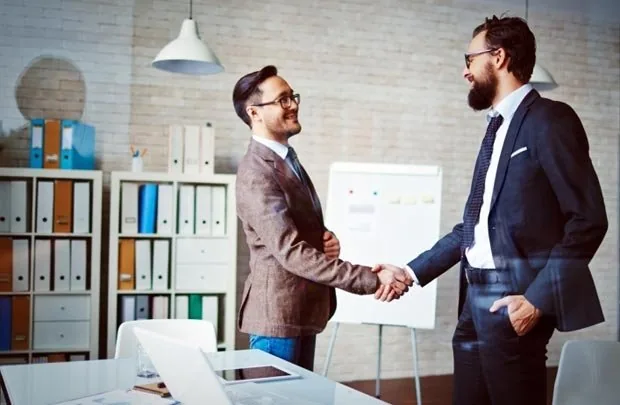 Hai doanh nhân bắt tay trong văn phòng, minh họa làm việc tại Mỹ với visa L1