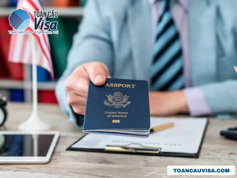 Tay cầm hộ chiếu Mỹ trên bàn làm việc, các loại thị thực định cư Mỹ